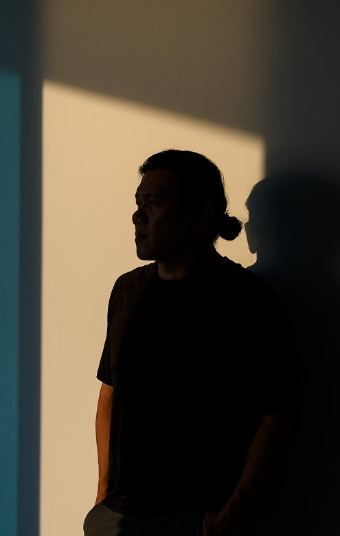 A person standing in shadow against a sunlit wall